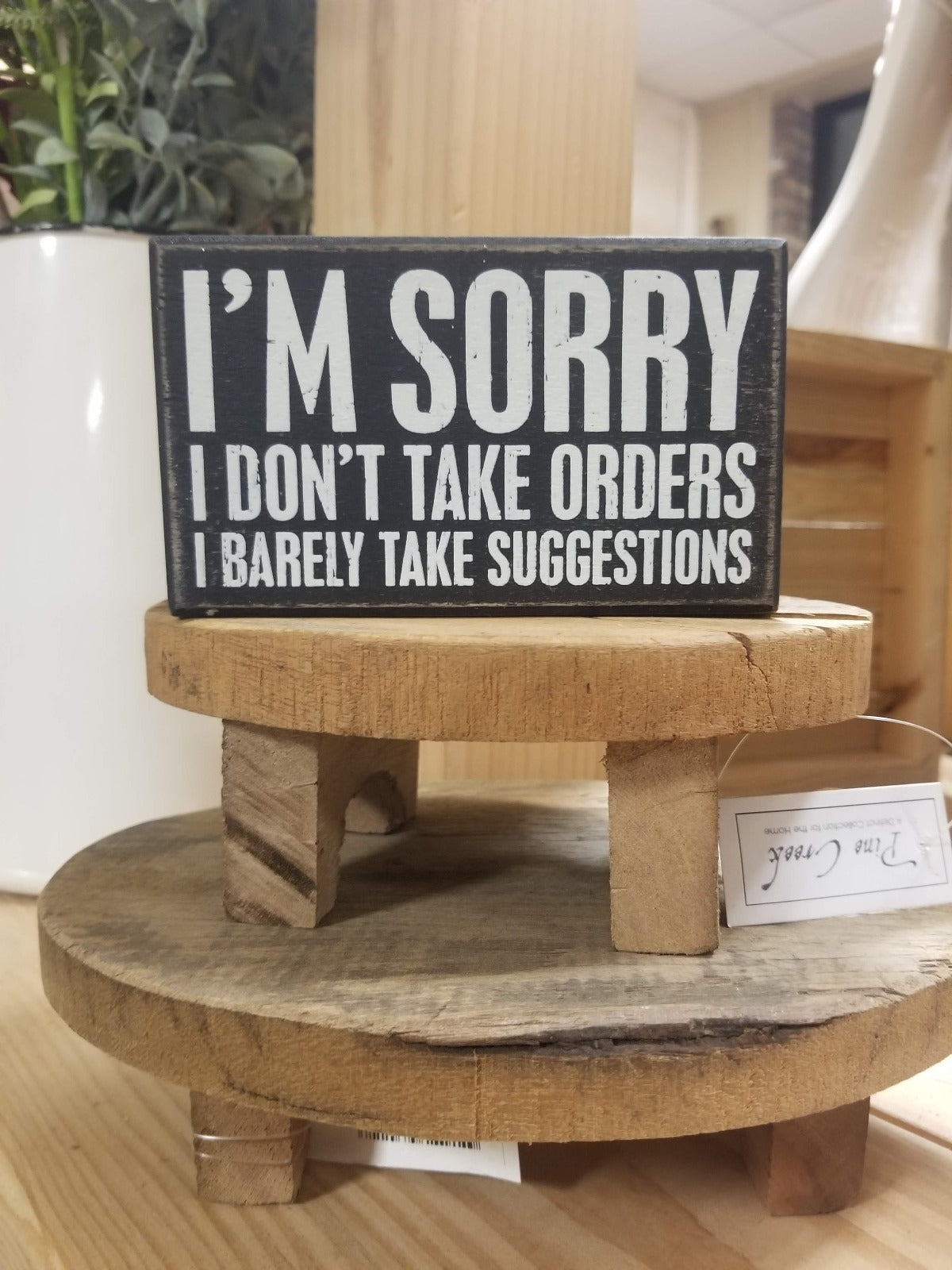 Rustic black and white box sign featuring humorous text, that reads, "I'm Sorry I Don't Take Orders I Barley Take Suggestions"