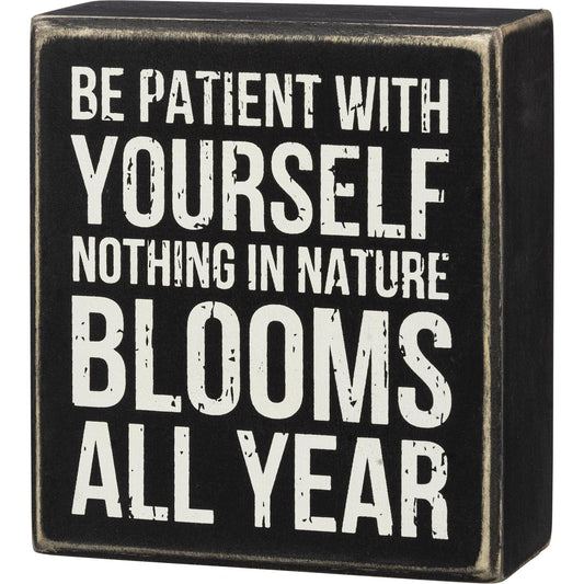 A classic wooden box sign featuring a "Be Patient With Yourself Nothing In Nature Blooms All Year" sentiment.