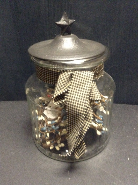 Glass jar with black metal cover with star on top for character. also ribbon tied around the neck as an accent that make it pop