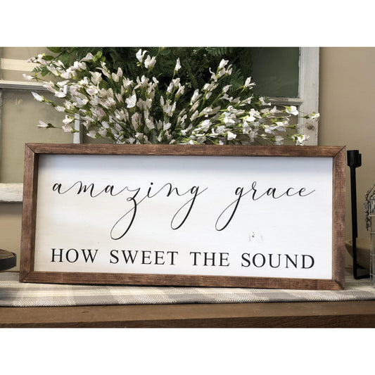Wall Hanging / Sign with white background and black lettering, finished with a stained wooden frame. "Amazing Grace, How Sweet The Sound"
