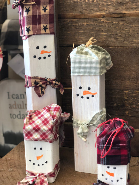 Standing snowmen available in different sizes. Made using wood and accented by hats and scarfs using pieces of fabric, each with different patterns and colors! The only thing left to do after those steps were to give each of them, eyes, nose, and mouth