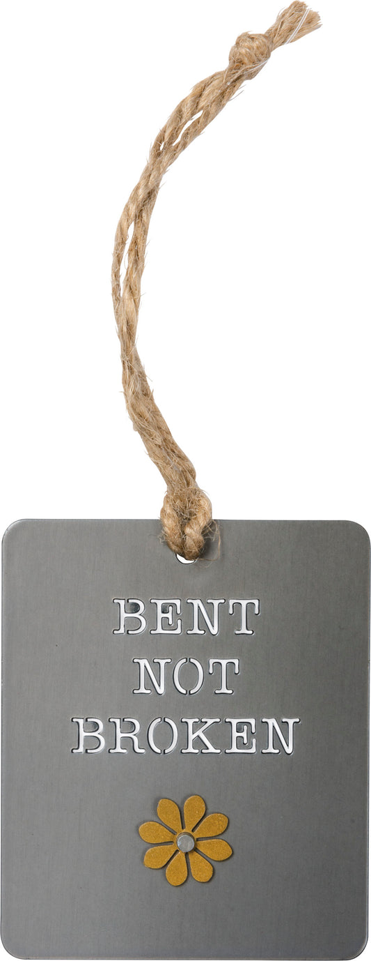 A metal ornament lending a "Bent Not Broken" sentiment. Features riveted dimensional accent and jute string attachment for easy hanging
