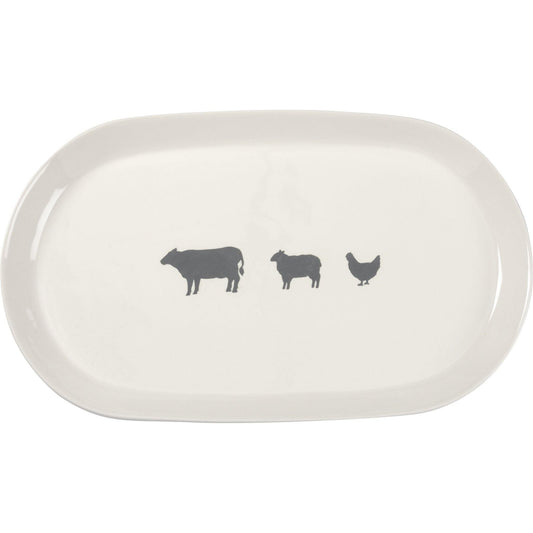 A white stoneware oval platter featuring a gray cow, sheep, and chicken design in the center