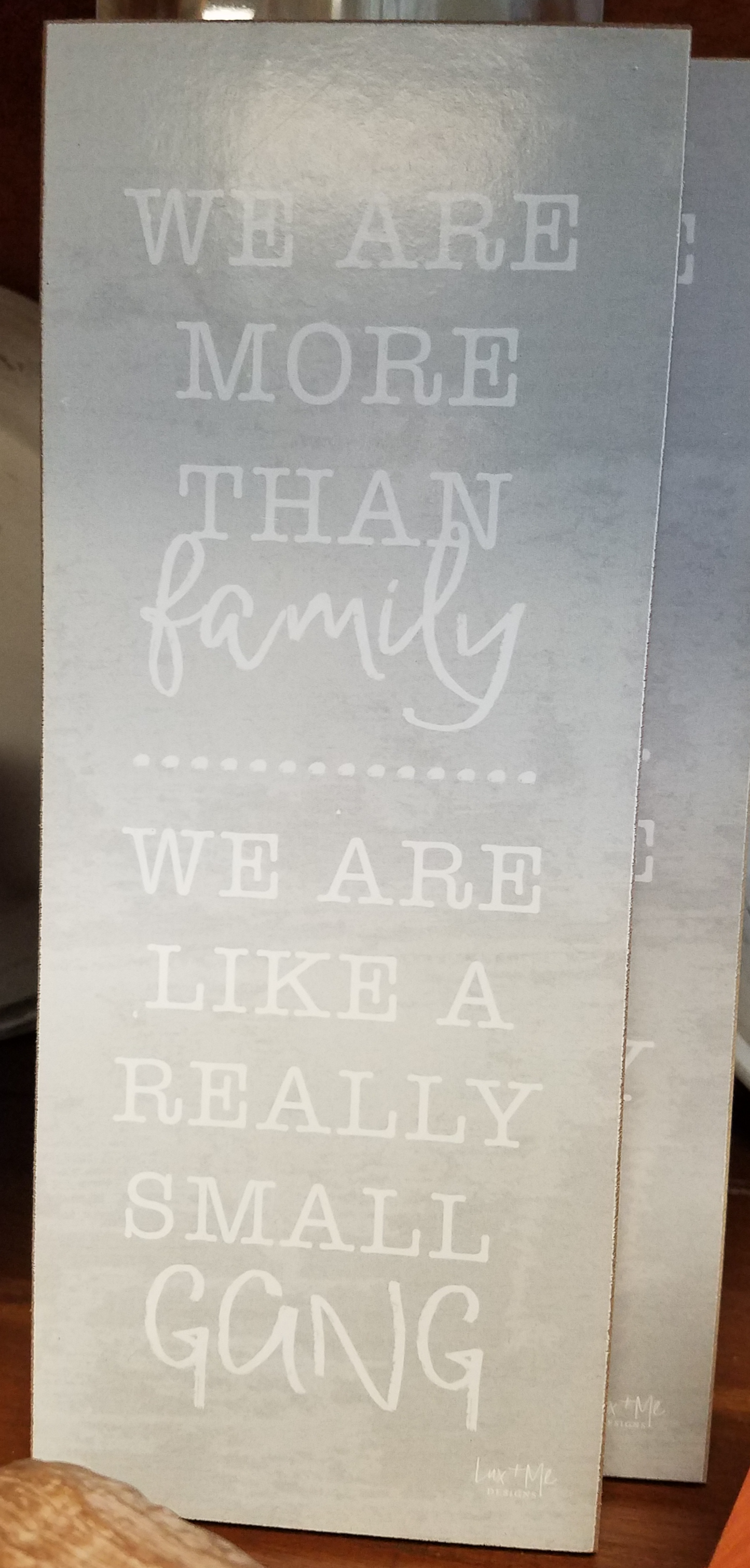 Gray sign with white letter that read, "We are more than family, we are like a really small GANG"