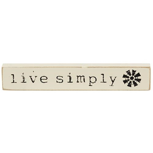 Live Simply Mini Stick is a wooden quote stick that comes in three assorted designs. Each stick reads, "gather," "bless our home," or, "live simply" and is accented with farmhouse illustrations like five-point stars, a crow, and a windmill. Stick has a flat bottom for shelf or tabletop display and measures 1" high by 6" wide.